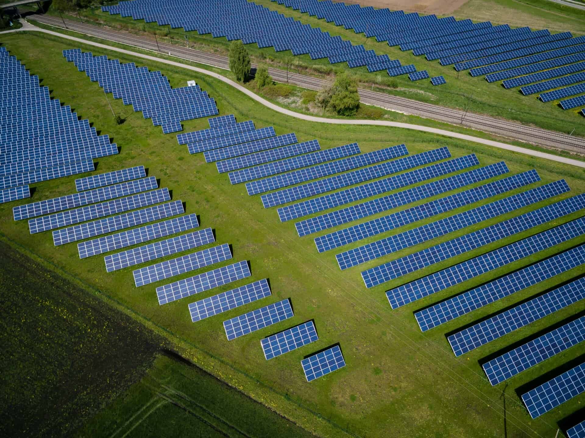 imagine descriptiva cu un camp unde se afla mai multe panouri fotovoltaice, datorita conditiilor nefavorabile putem vedea durata de viață a panourilor fotovoltaice